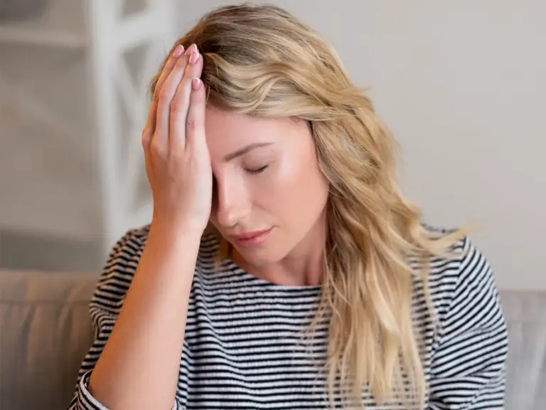 Woman resting a hand against her forehead with her eyes closed