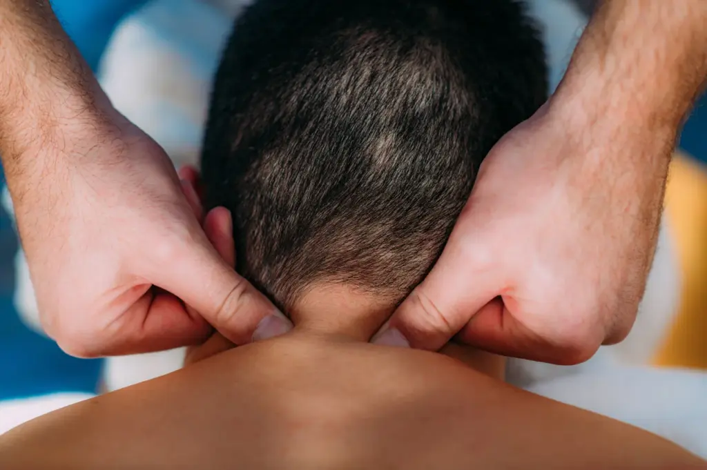 Therapist's hands working the muscles at the base of a patient's neck