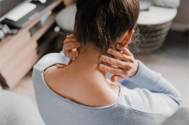 Woman seen from behind with both hands gripping the base of her neck