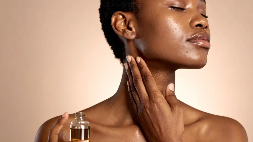 Woman applying facial oil along her jawline and neck