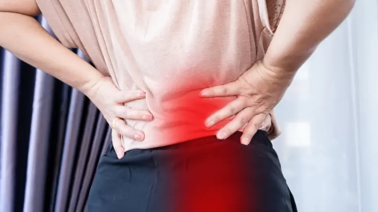 Woman with both hands on her lower back and hip, the painful area highlighted