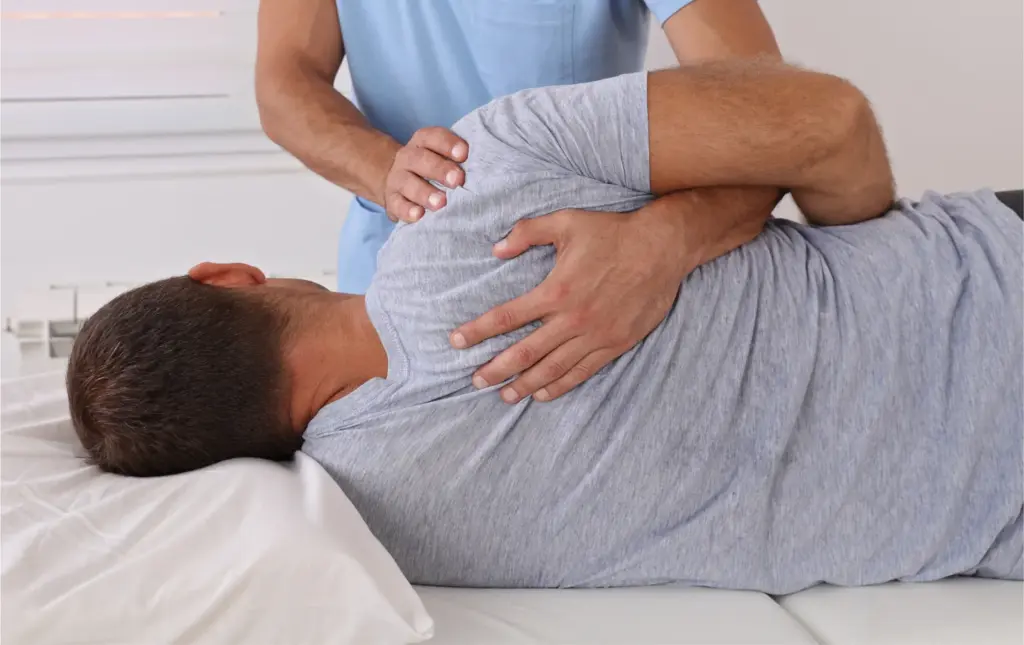 Chiropractor performing a side-lying adjustment on a patient lying on a treatment table